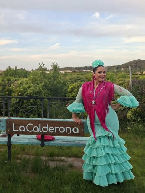 Invitada vestida de flamenca junto al cartel de La Calderona