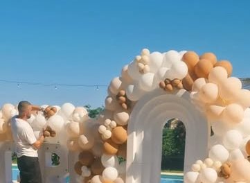 Arco de globos blancos y dorados junto a la piscina