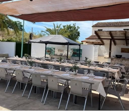 Mesas largas preparadas bajo la pérgola para un bautizo